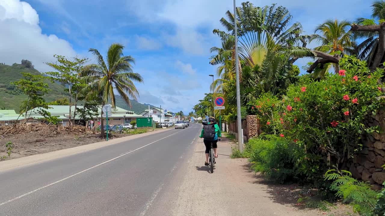 A tourist cycling on road with quiet traffic whilst on holiday on tropical Moorea Island in French Polynesia, South Pacific