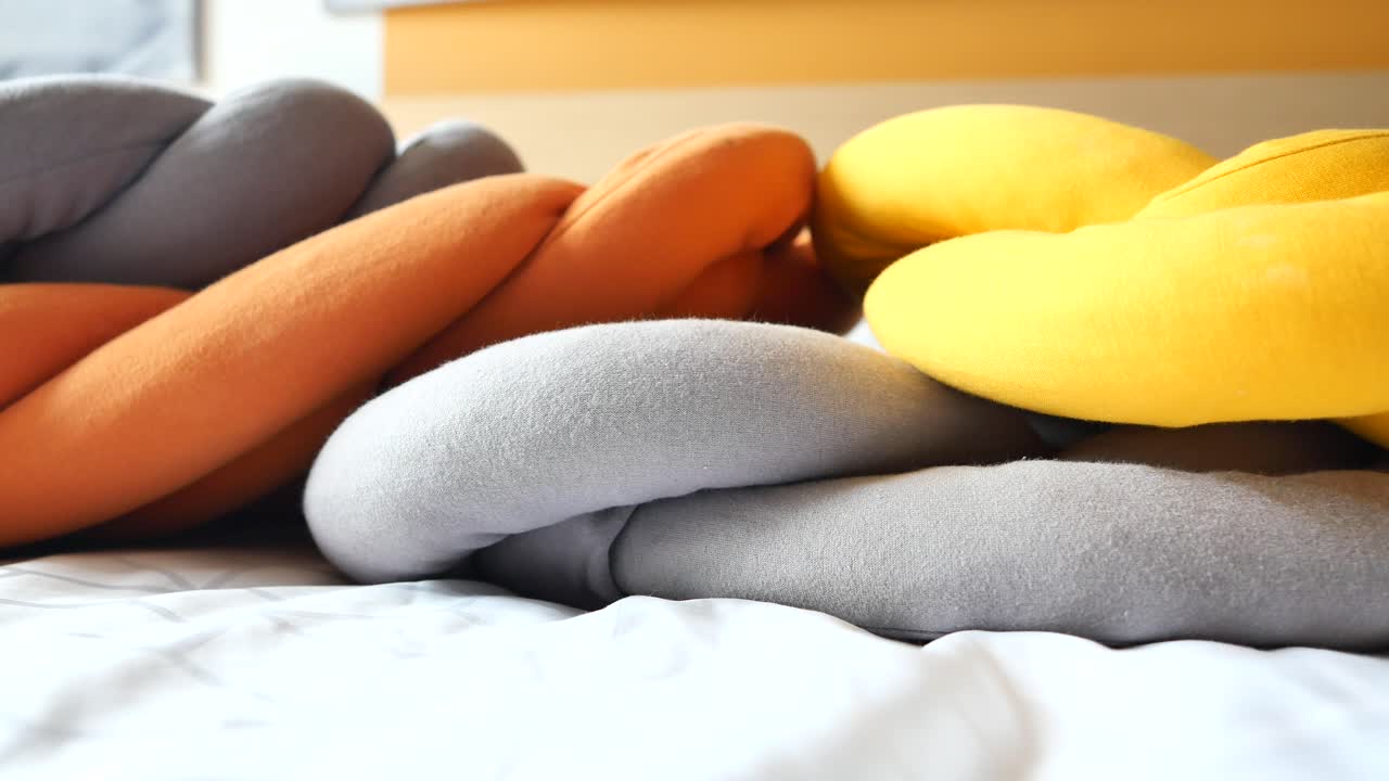 almohadas anudadas trenzadas coloridas en una cama