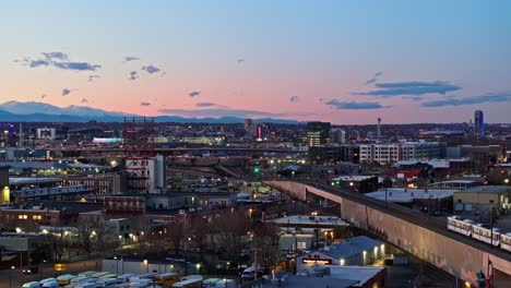 Wide-angle-descend-above-serene-city-scene-and-trendy-shops-as-train-drives-by,-aerial