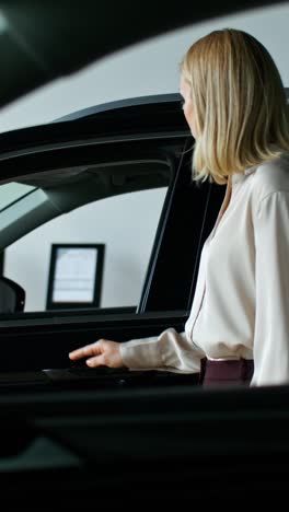 woman looking at a black car in a showroom