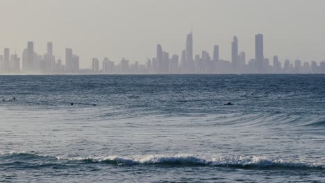 surfers and waves with distant city skyline