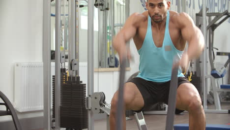 joven musculoso trabajando con cuerdas de batalla en un gimnasio