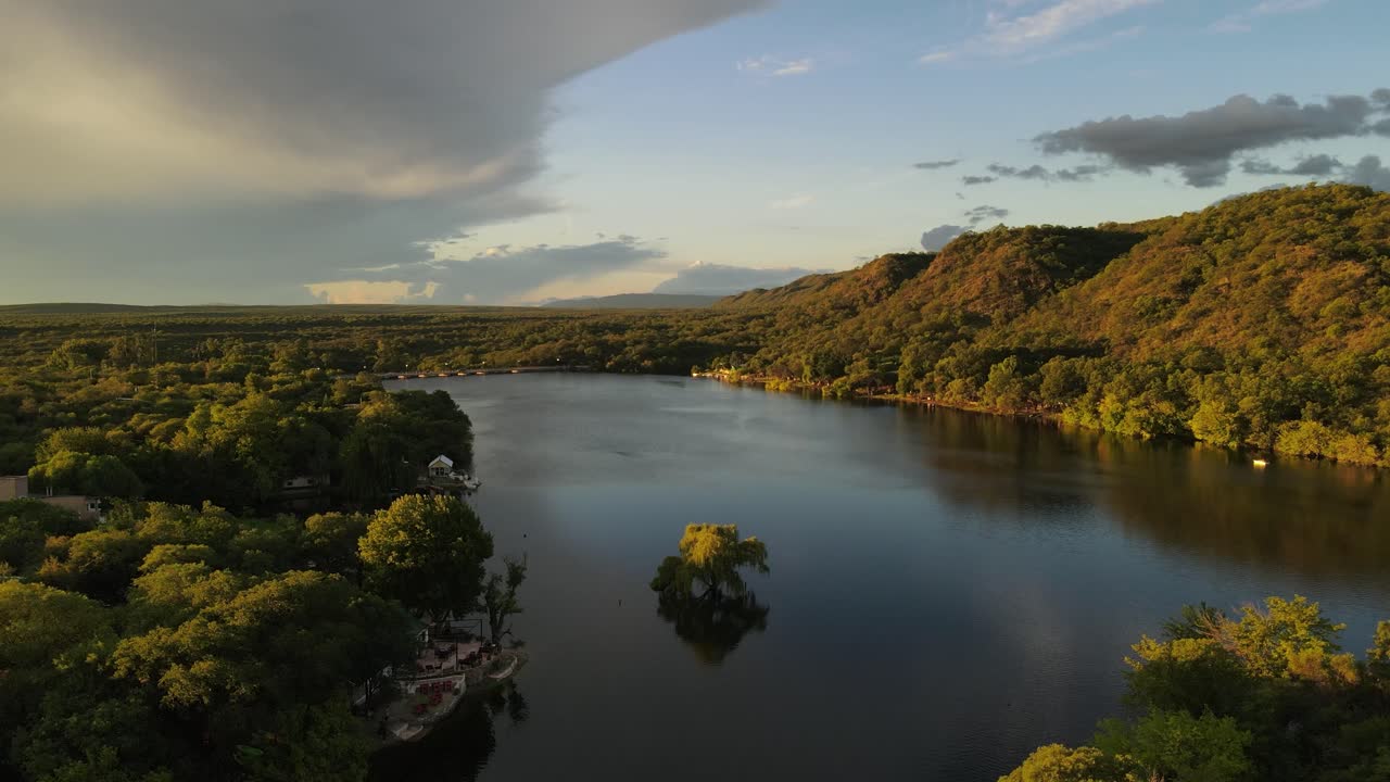 lago rodeado de verdes colinas al atardecer, córdoba en argentina