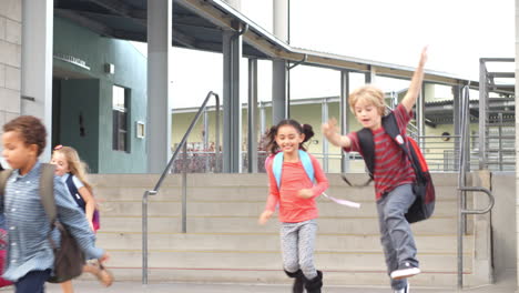 young school kids jumping down steps as they leave school