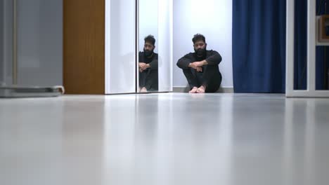 un hombre que sufre un episodio psicótico solo sentado en el suelo.