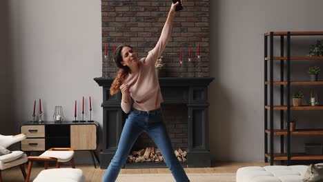 happy emotional energetic young woman dancing with telephone in hands.