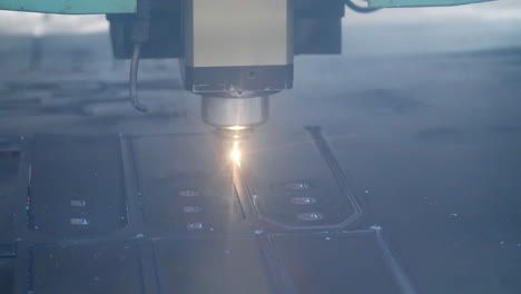 close up of laser cutting of metal sheet with bright sparkles at factory