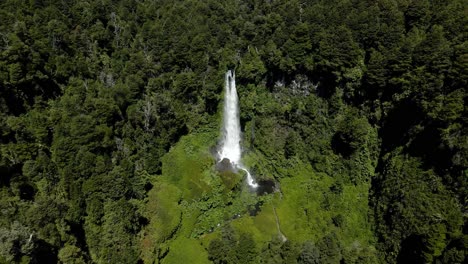 panoramic orbit of the waterfall el salto el leon in the south of chile with vegetation around it on a sunny day - aerial