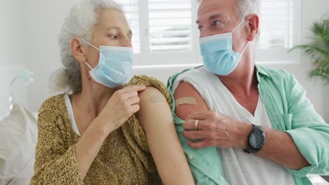 caucasian senior couple wearing face masks and plasters after vaccination