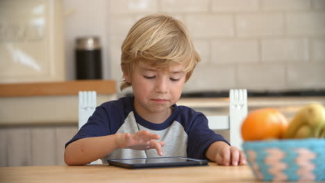 young boy using tablet computer at kitchen table, pan