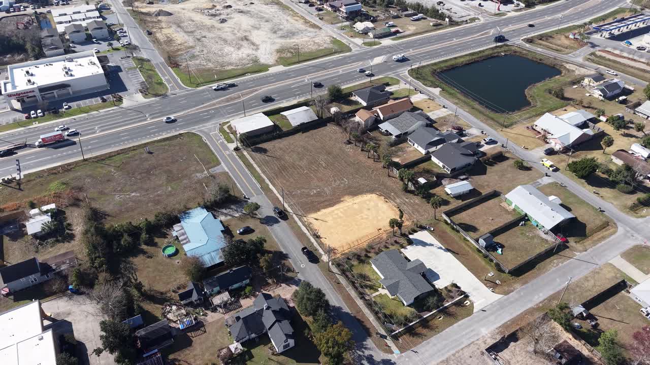 Drone orbit around developing empty plot of urban neighborhood with surrounded houses, Panama City, Florida, USA