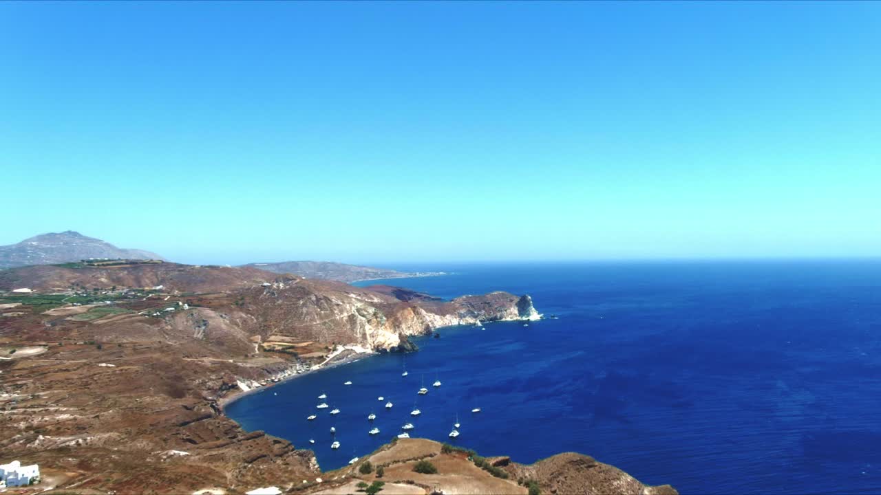 vista aérea 4k azul del mar y el cielo con veleros atracados en la arboleda de la ladera en santorini grecia