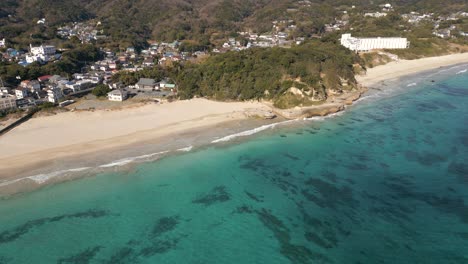 Drone-flying-closer-to-beach-with-beautiful-turquoise-waters-in-Japan