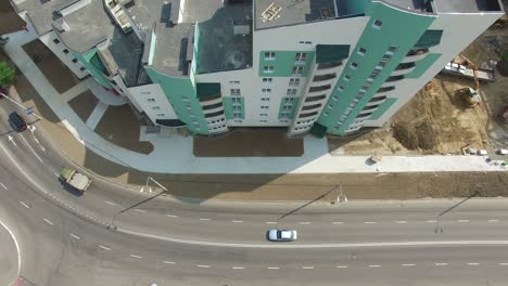 top view of a big modern building standing close to the wide road with cars in the city. new multy-storey building. camera moves top down