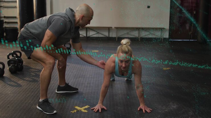 Female client pushing up after trainer tactile cue, improving fitness form with teal dotted overlay