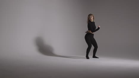 foto de estudio de longitud completa de una mujer joven haciendo práctica de baile contra fondo gris 2