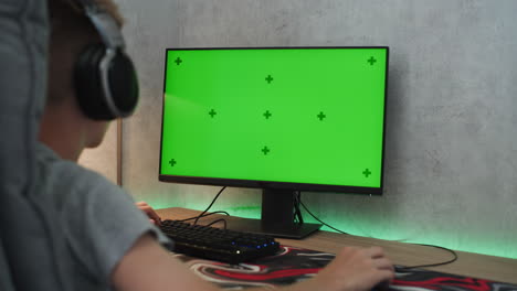 person gaming with green screen monitor