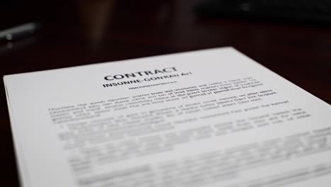 a close-up view of a contract document highlighting important terms and conditions related to an insured entity, set against a professional workspace background