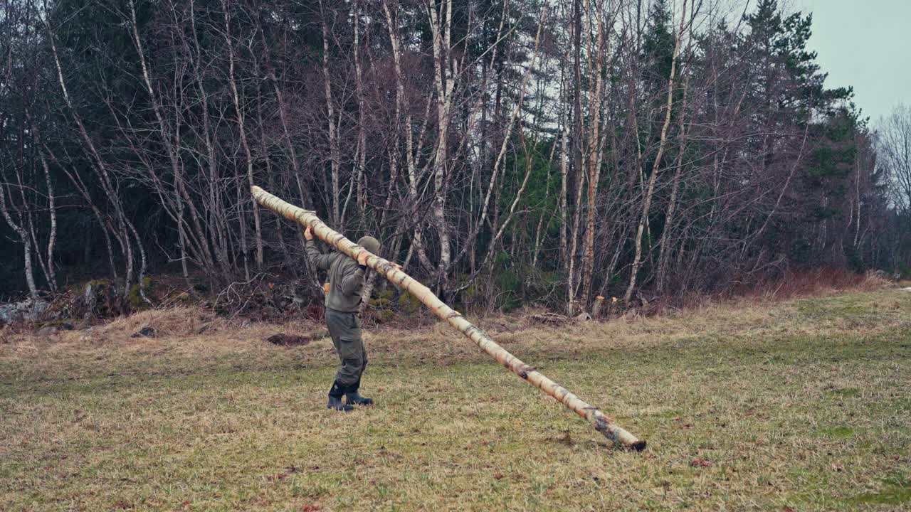 Man Carrying A Tree Trunk For Firewood - Wide Shot