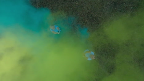 two friends playing with smoke bombs in a field