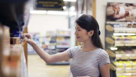 and asian girl visitor chooses one of two products. happy shot visitor. choice of products in the store