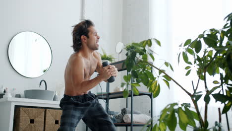 man singing karaoke in the bathroom with a hair dryer