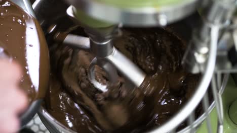 mixing chocolate cake in large mixer. a baker uses a professional large mixer to whip up some chocolate mix