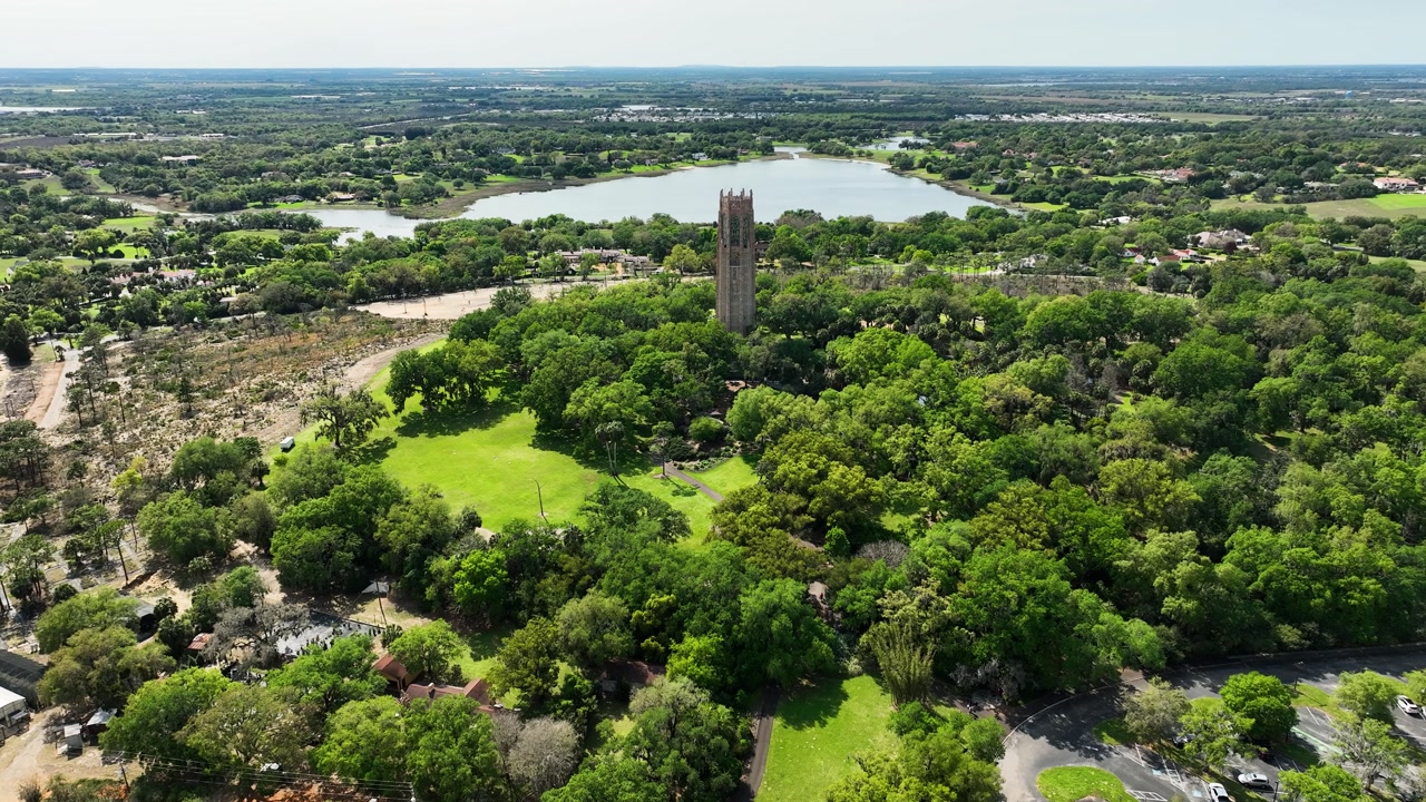 A tranquil drone perspective showcases Bok Tower nestled within expansive gardens and forested land in Lake Wales, Florida.