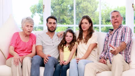 extended family watching television on the sofa