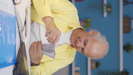 Vertical-video-of-Home-office-worker-old-man-counting-money-funny-and-funny.