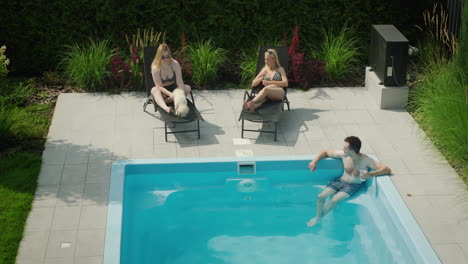 a man with a cocktail is relaxing in the pool, next to two beautiful women. dream vacation