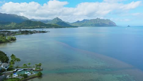 Toma-Aérea,-Drone-Volando-Sobre-El-Océano-Pacífico-En-Oahu-Hawaii,-Rancho-Kualoa-En-El-Horizonte-Con-Nubes-Arriba