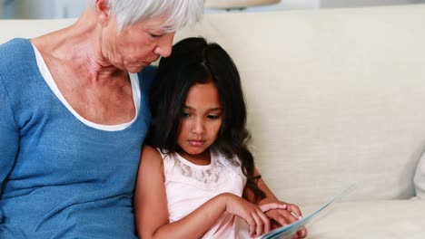 grandmother and granddaughter interacting while looking at photo album in living room