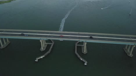 Drohnenaufnahme-Eines-Bootes,-Das-Um-Eine-Brücke-Herumfährt