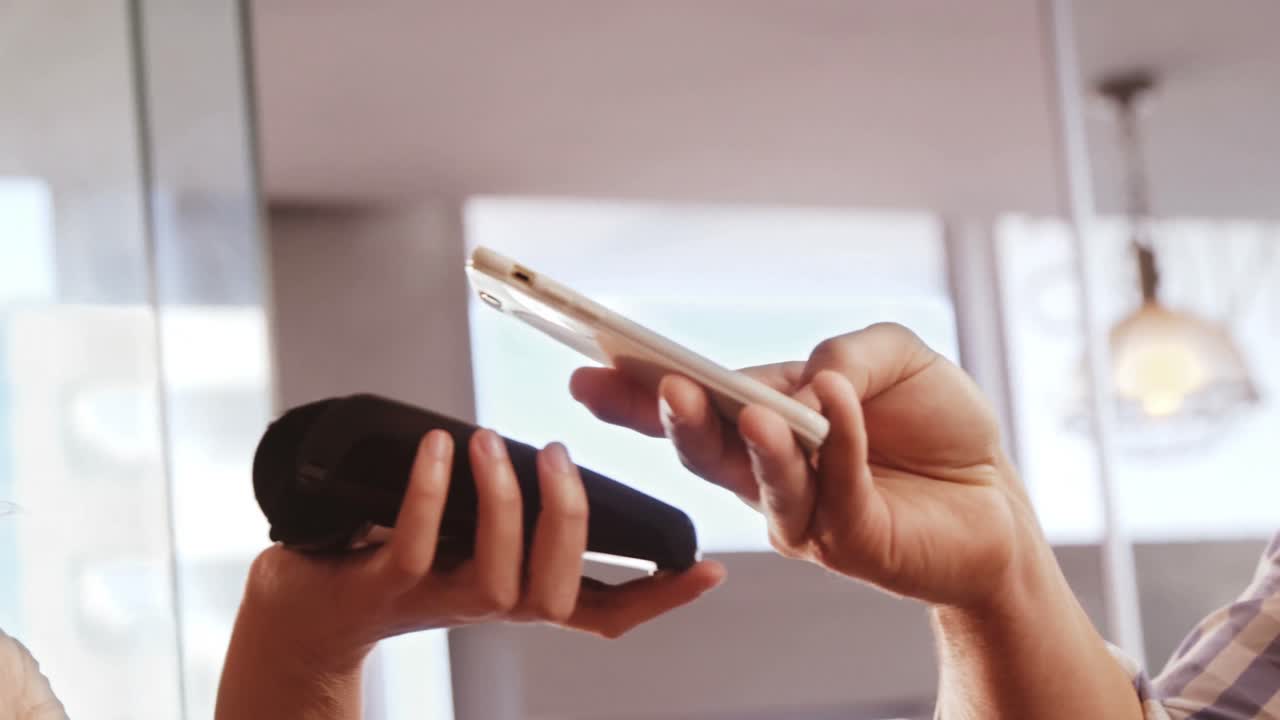 hombre pagando facturas a través de un teléfono inteligente utilizando tecnología nfc