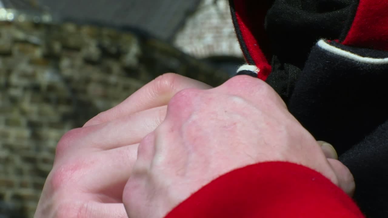 French Napoleon soldier closes the buttons of his costume. Close shot on hands
