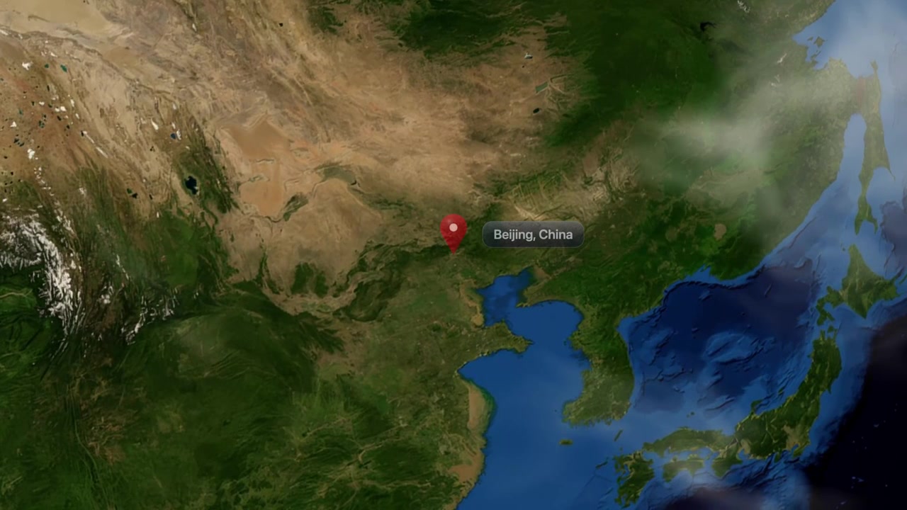 Satellite camera zooms from outer space into East Asia, marking Beijing, China with pin. Includes NASA public domain imagery.