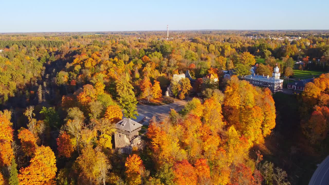 Aerial panoramic ascend to Sigulda Castle and surrounding autumn forests in Latvia, showcasing scenic fall colors and historic architecture