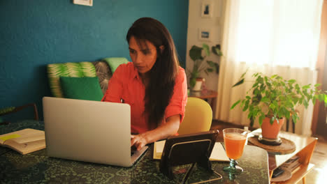 Woman-using-laptop-and-digital-tablet-at-home-4k