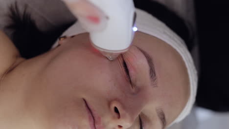 esteticista hace a la mujer rf lifting procedimiento de cosmetología de la cara y los ojos mascarilla de colágeno en el spa