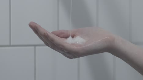 woman pours soap into her hand in the shower