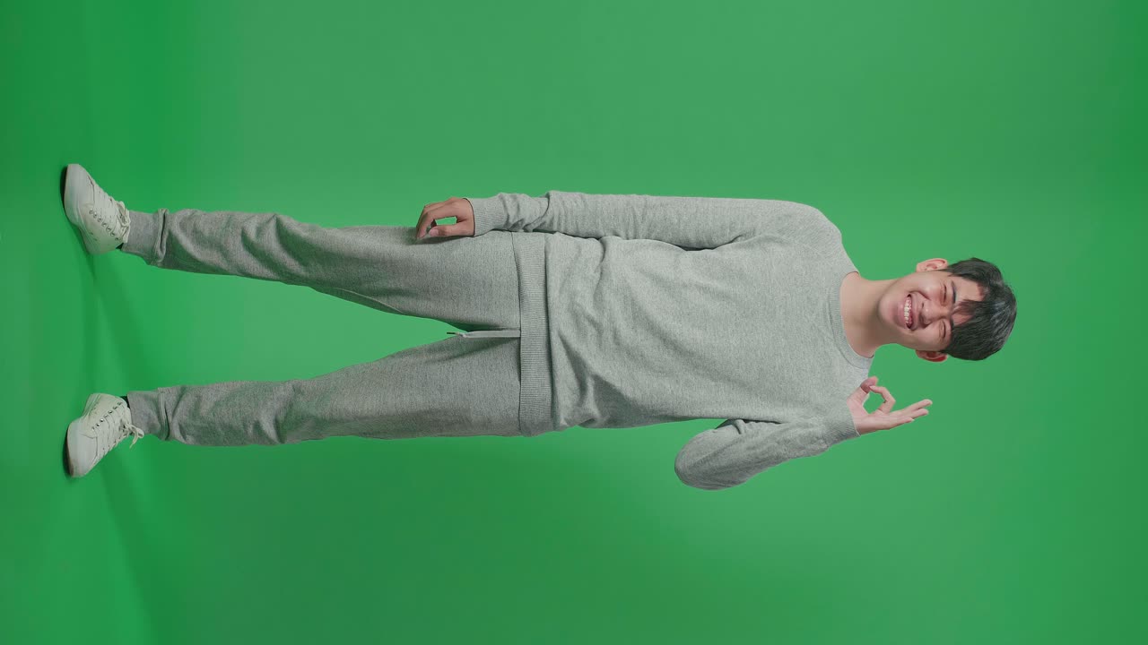 Full Body Of Happy Asian Man Showing Okay Gesture To The Camera In The Green Screen Studio