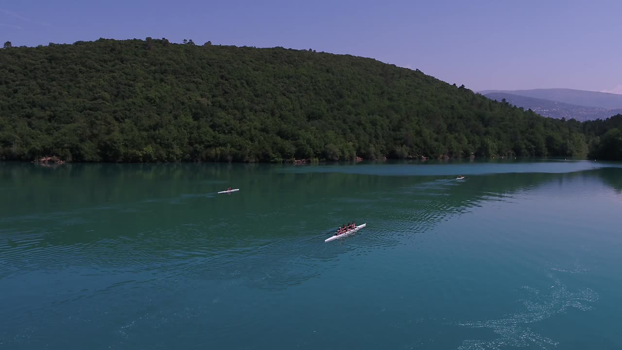 gente disfrutando de las aguas de francia por hermosas montañas verdes y exuberantes en sus canoas - antena baja