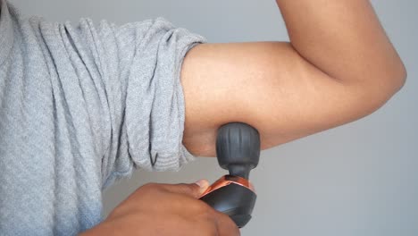 person using massage gun on arm