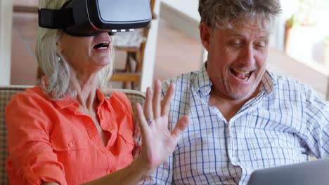 pareja de ancianos usando portátil y auriculares de realidad virtual en el sofá 4k