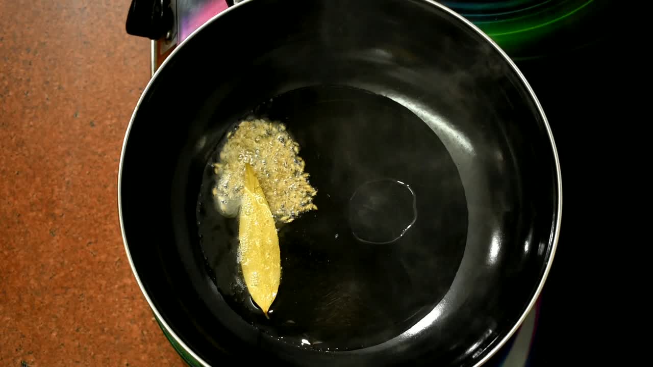 close up of spices and chopped onion into a frying pan