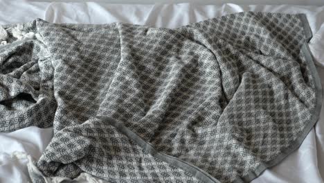 gray and white checkered blanket on a white bed