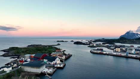 aaerial of svolvaer harbor facing calm sea and glowing midnight sun horizon