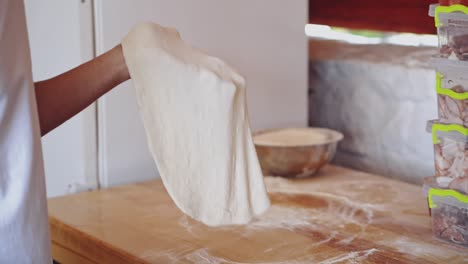 male hands prepares dough for pizza. baker making pizza dough on wooden table before baking. cook forming the dough with his hands on a round deco. close-up.