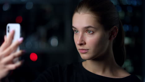 Side-portrait-view-of-serious-girl-taking-selfie-on-her-iPhone.-Woman-unlocking.